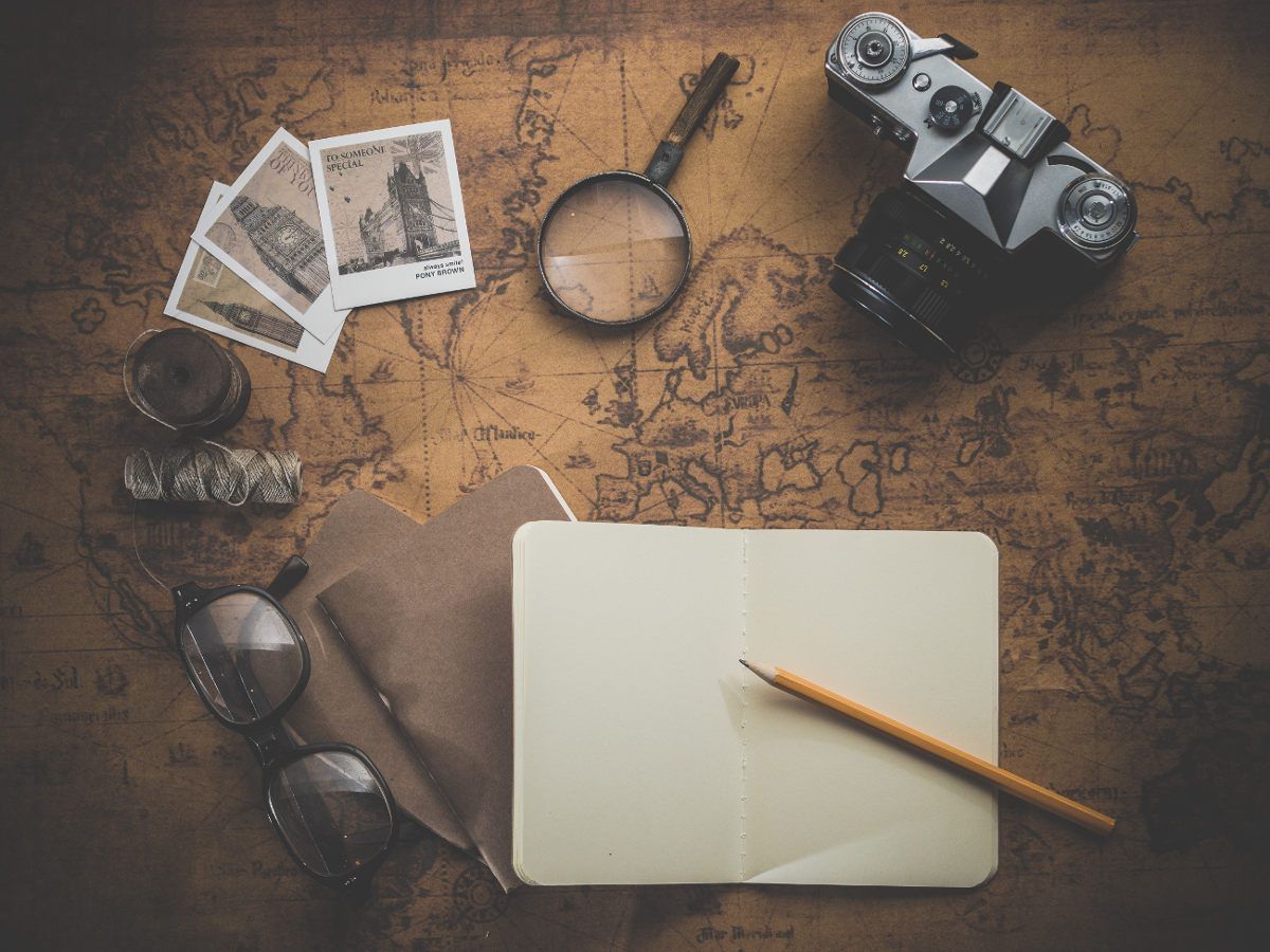 Mapa antiguo con lupa, cámara de fotos, cuaderno y gafas
